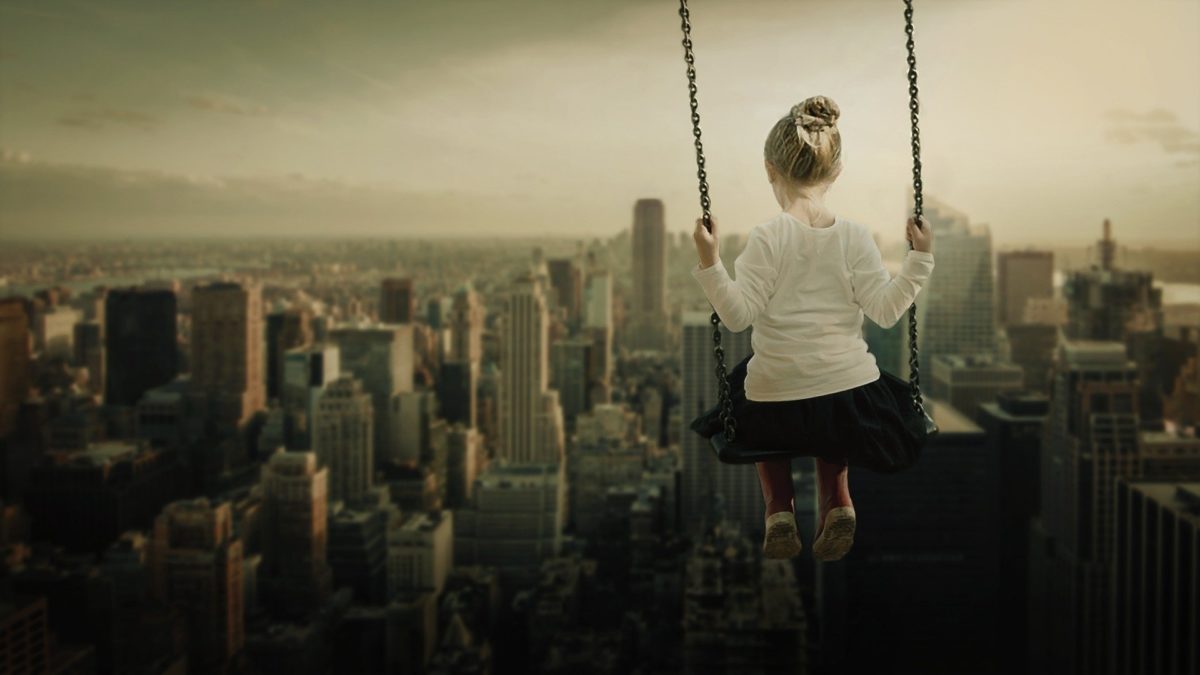 niña en un columpio en el cielo de una ciudad