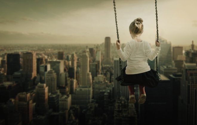 niña en un columpio en el cielo de una ciudad